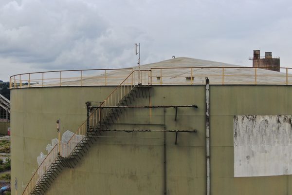 A large industrial storage tank with an external access stairway and handrails