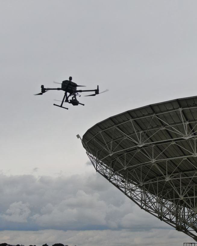 A telecommunications tower being inspected by a drone