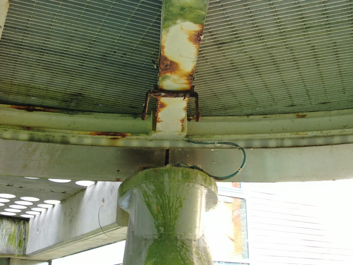 A view looking up at of the arms of the tetrapod pier showing some corroded areas of the soffit and also a missing light fixture.