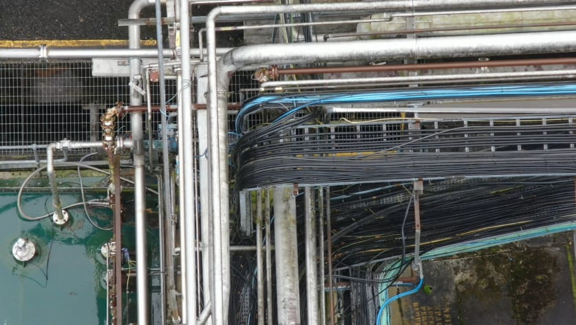 Stainless steel and steel pipe and electrical power and signal cable racks as seen during an inspection