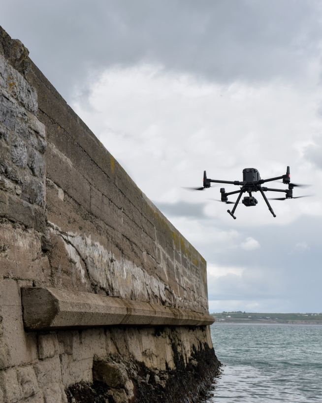 A DJI inspection drone inspecting the wall of a coastal pier