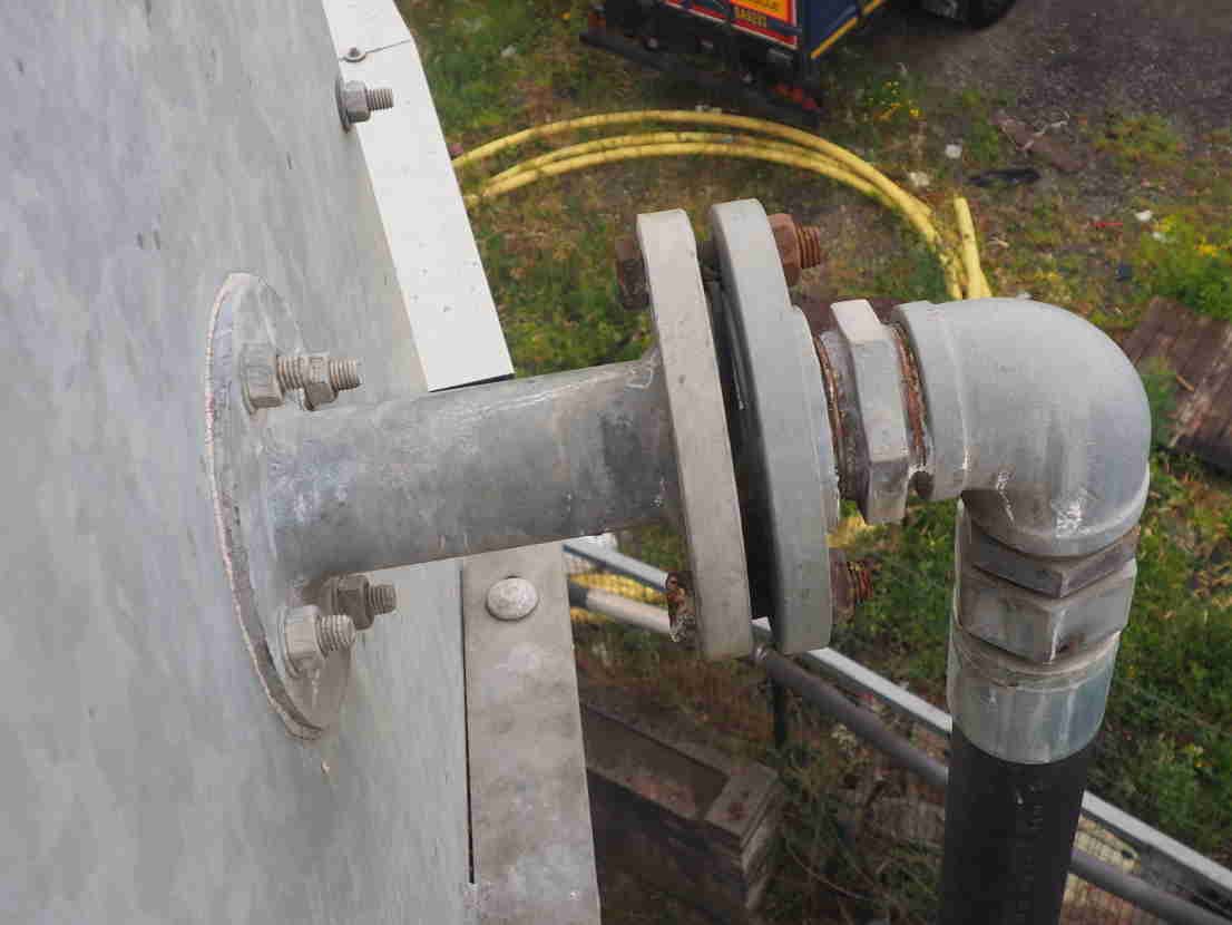 A flanged pipe joint with two of the securing bolts missing.